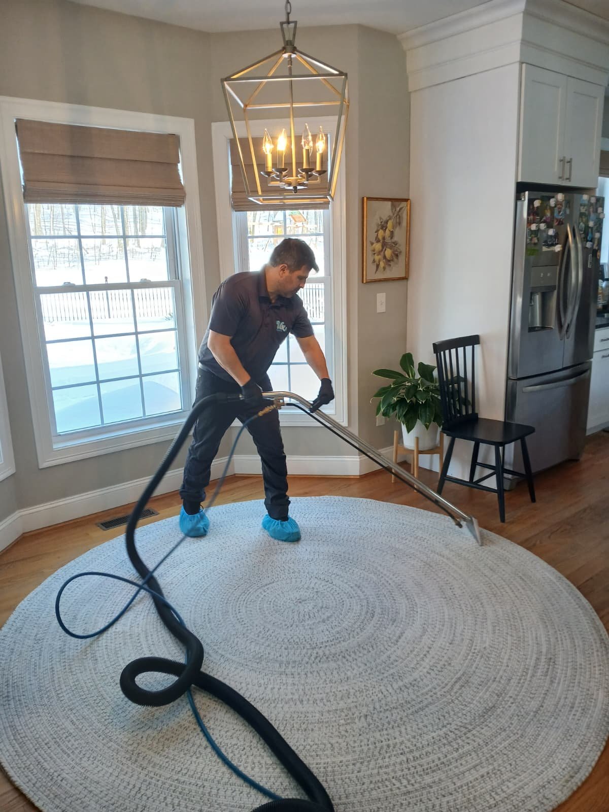 Vix steam-cleaning a large round area rug in a customer's kitchen nook